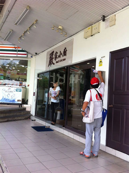 A campaign distributor outside shops in a commercial neighbourhood.
