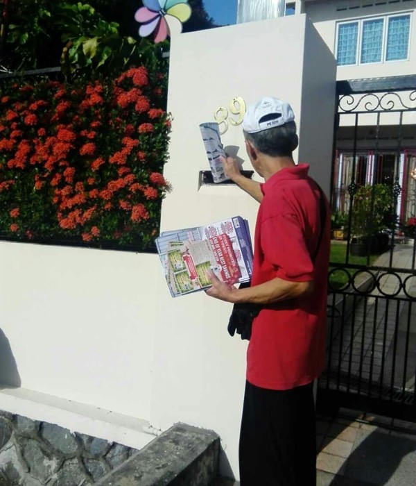 A distributor carrying campaign materials in a landed residential area.