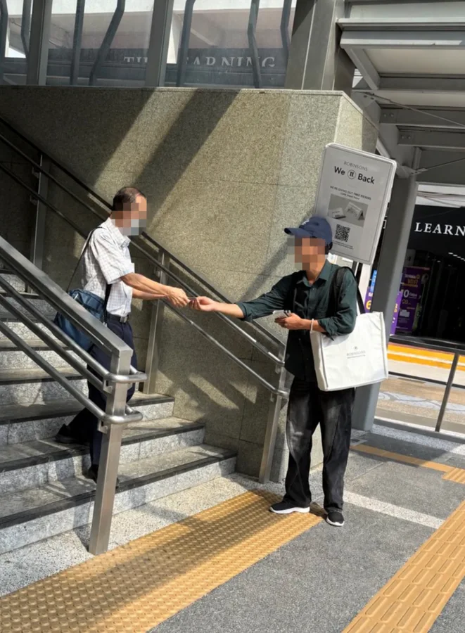 Promotional tissue packs handed to passers-by, supported by a backpack advertising board.